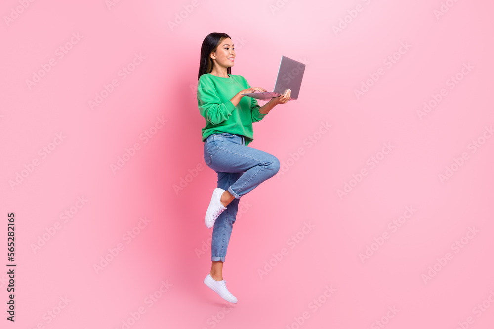 Full size portrait of excited pretty girl jumping use wireless netbook isolated on pink color background Full size portrait of excited pretty girl jumping use wireless netbook isolated on pink color background