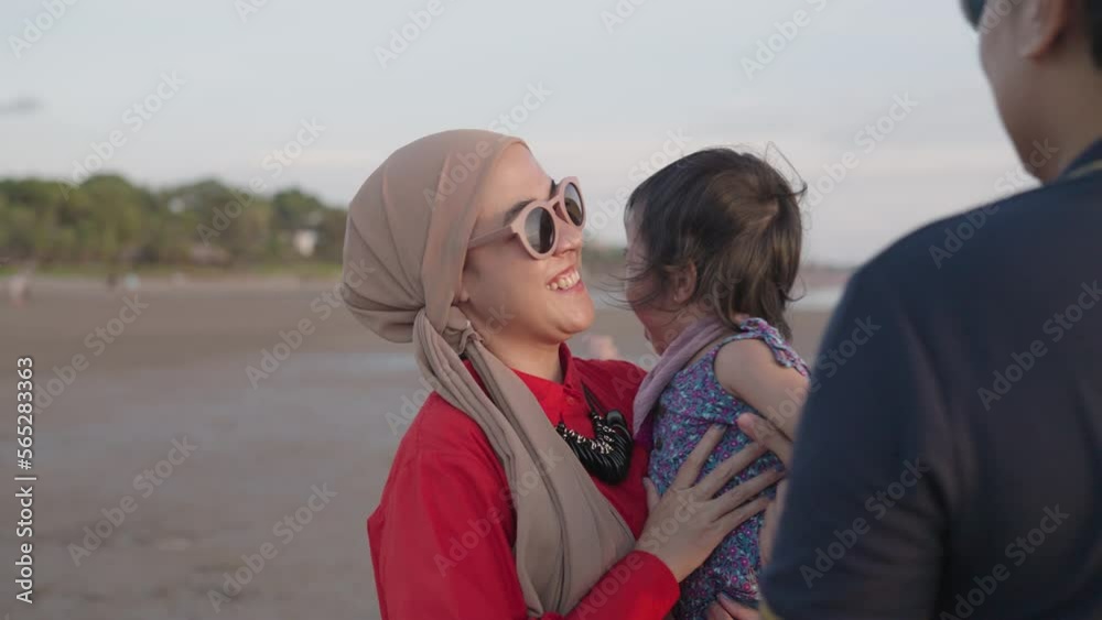 Happy Modern Muslim Southeast Asian Indonesian Family Enjoying Sunset Together on The Beach. Silhouette of Father Mother and Child in Slow Motion. Happy Modern Muslim Southeast Asian Indonesian Family Enjoying Sunset Together on The Beach. Silhouette of Father Mother and Child in Slow Motion.