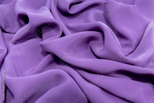 The texture of a smooth elegant fabric of silk, satin blue, purple with folds and waves. Stylish material with wrinkle and bumps photo