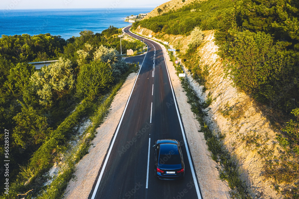 Driving on a coast road. Aerial view of a car driven on an amazing curved waving road at the Sea shore in Balchik sea resort in Bulgaria.