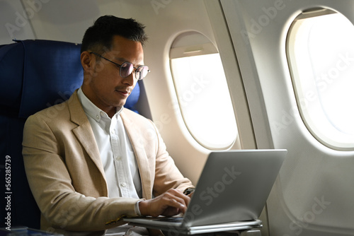 Image of businessman passenger sitting comfortable seat working with laptop on airplane cabin © Prathankarnpap