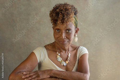 Beautiful elderly retired black African-American woman in her 70s wearing earrings and necklace looking at camera with knowing expression