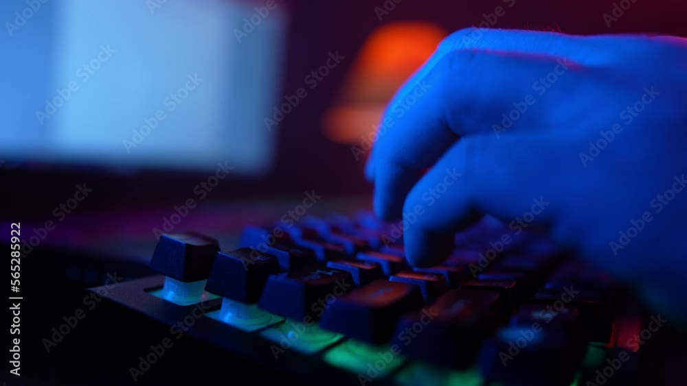 Close-up, Unrecognizable Man Using a Computer Keyboard to Code a Website in Neon Lighting. Hacker and Cybercrime or Cyberspace Concept. Close-up, Unrecognizable Man Using a Computer Keyboard to Code a Website in Neon Lighting. Hacker and Cybercrime or Cyberspace Concept.