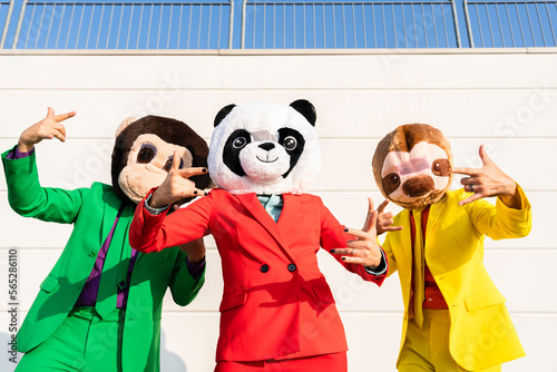 Women gesturing with men wearing animal masks in front of wall photo