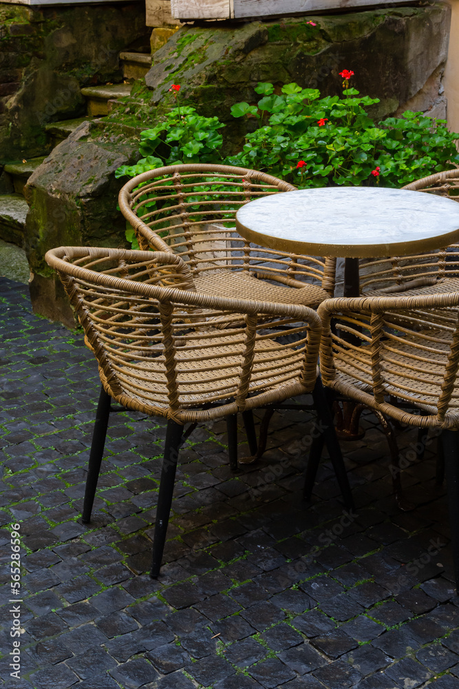 Obraz premium Empty wet wooden table and chairs on terrace of outdoor cafeteria during rain. Street city life in rain