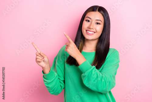 Photo of cheerful young positive vietnamese lady wearing green stylish sweater point fingers empty space deal promo isolated on pink color background © deagreez