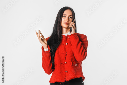 Serious charming brunette woman talking on mobile phone. Girl with mobile cell phone. Indoor studio shot on white background.