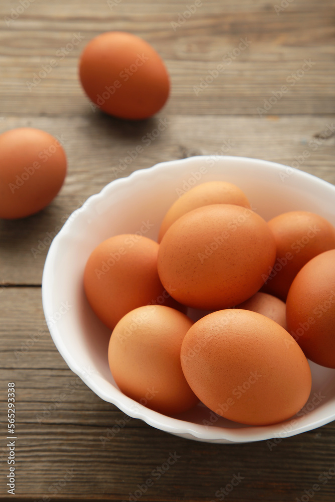 Top view of raw brown eggs on plate on grey wooden background. Eggs are a common ingredient in cooking. Vertical photo. Top view of raw brown eggs on plate on grey wooden background. Eggs are a common ingredient in cooking. Vertical photo.