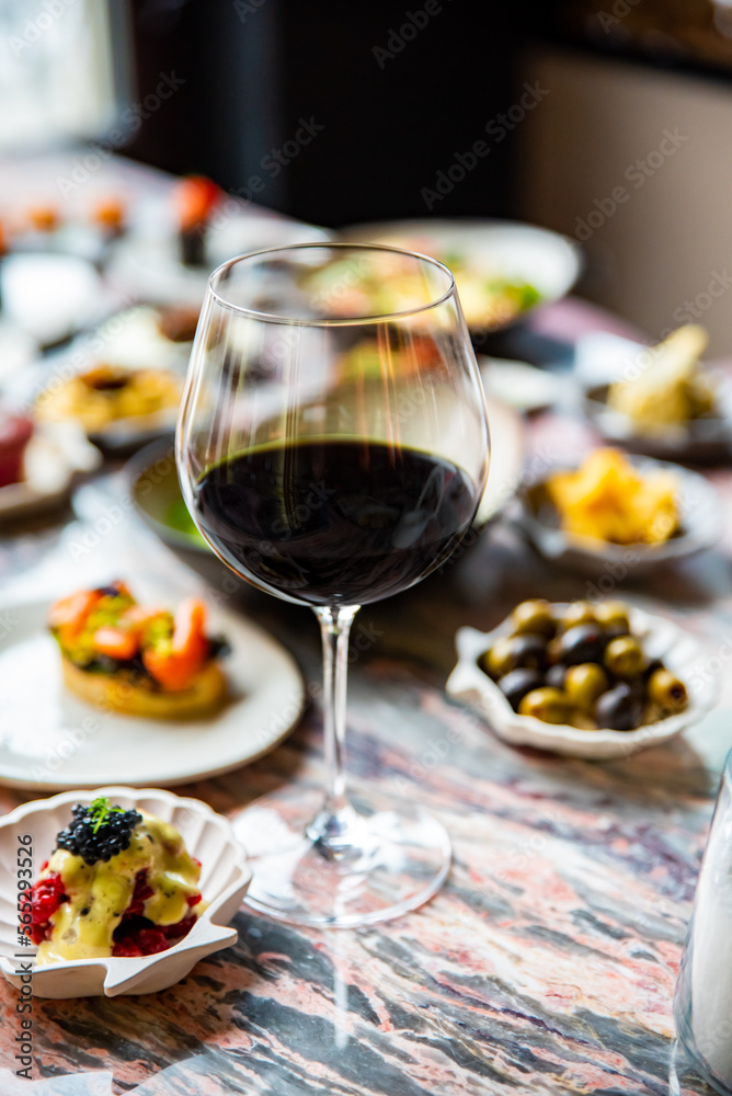 glass with red wine and wine snack set, food from spain, cheese, meat, vegetables and other appetizers on table glass with red wine and wine snack set, food from spain, cheese, meat, vegetables and other appetizers on table