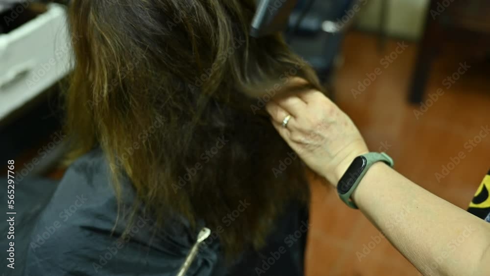 Hairdresser using a hair dryer for blowing water to dry her customer hair in barber shop. Hairdresser using a hair dryer for blowing water to dry her customer hair in barber shop.