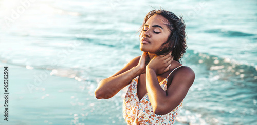 Relaxed african woman enjoying sun and freedom outdoors - Beautiful female breathing fresh air at the beach at sunset - Mental health, happiness and healthy lifestyle concept