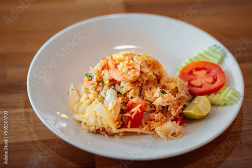 A plate of fried rice is on the table. A dish of fried rice with seafood and vegetables with the addition of an egg. Asian dish. 