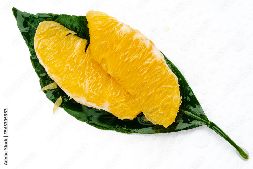 Peeled orange fruit pulp on green leaf isolated on white background. Macro photo of citrus fruit slice. Fresh, juicy pulp of orange