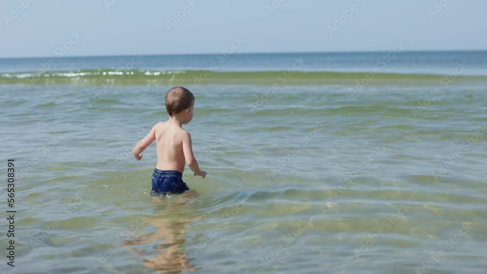 happy child boy kid playing bathing in sea ocean cold water kid jumping waves having fun laughing. summer vacations lifestyle. coastline seashore resort. child alone in water safety children on beach happy child boy kid playing bathing in sea ocean cold water kid jumping waves having fun laughing. summer vacations lifestyle. coastline seashore resort. child alone in water safety children on beach