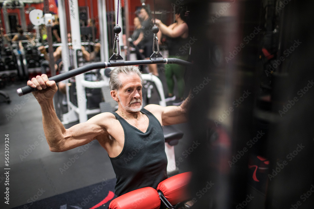 Front view of elderly man doing Lat Pull Down exercise at gym