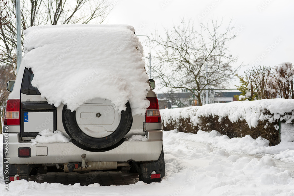 Mały , terenowy samochód produkcji japońskiej , pokryty sporą ilością śniegu , zaparkowany na zaśnieżonym parkingu osiedlowym . - obrazy, fototapety, plakaty 