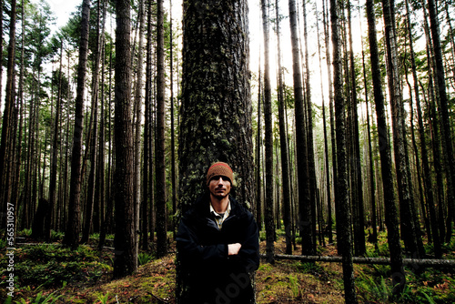 Self portrait of Jordan Siemens leaning against one of many trees in a thick forest. photo