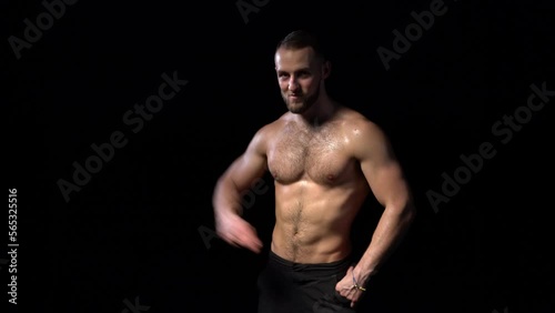 Shirtless muscular man dancing happy on black background, locked down real time video