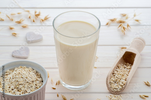 vegan and plant based oat milk in a glass, cereal grain around, plant milk