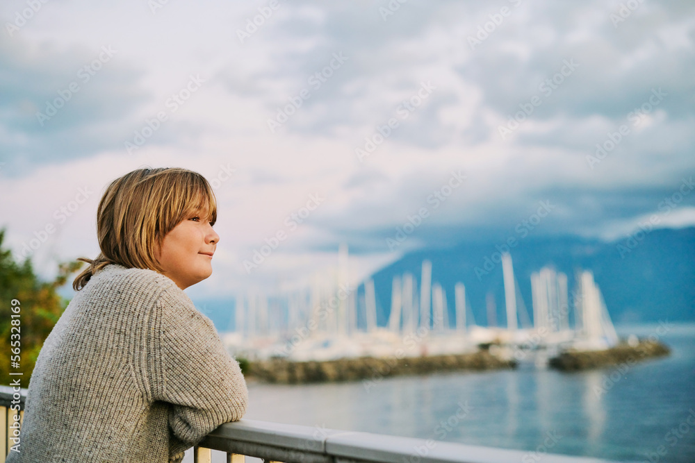 Fototapeta premium Outdoor portrait of happy preteen boy admiring beautiful water landscape, image taken in Lausanne, Switzerland