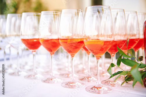 Many glasses with italian cocktail Aperol Spritz. Orange drink with liqueur and orange. Summer open air bar counter. Outdoors party celebration, welcome beverage.
