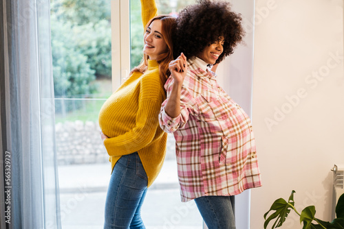 Two pregnant young women spending time dancing together. Concept: motherhood, loyalty, friendship