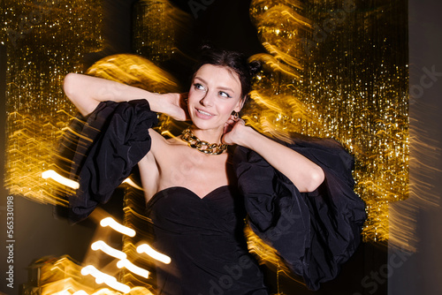 Stylish student girl dancing in a nightclub. Holiday atmosphere. Black and gold dress trend. Disco party. Attractive glamor sexy young woman. Night life emotions. Birthday celebrations. blur motion