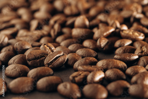 Roasted coffee beans background. Many aromatic coffee beans on a dark background. Selective focus. Close-up. The concept of an advertising banner for a coffee shop or chain of commodity production.