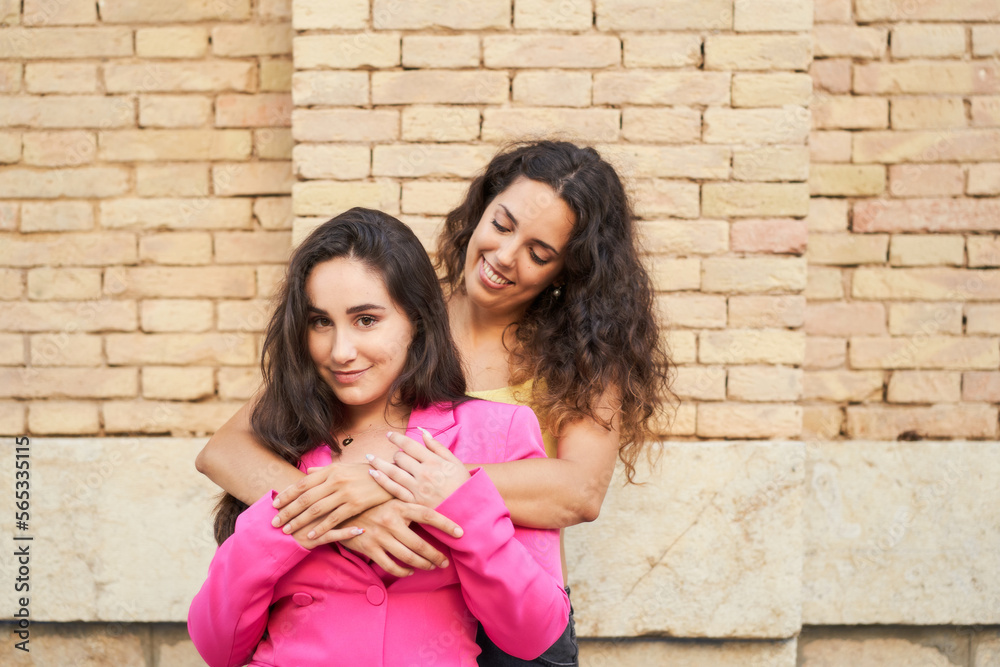 two young women friends embrace each other smiling with joy at meeting