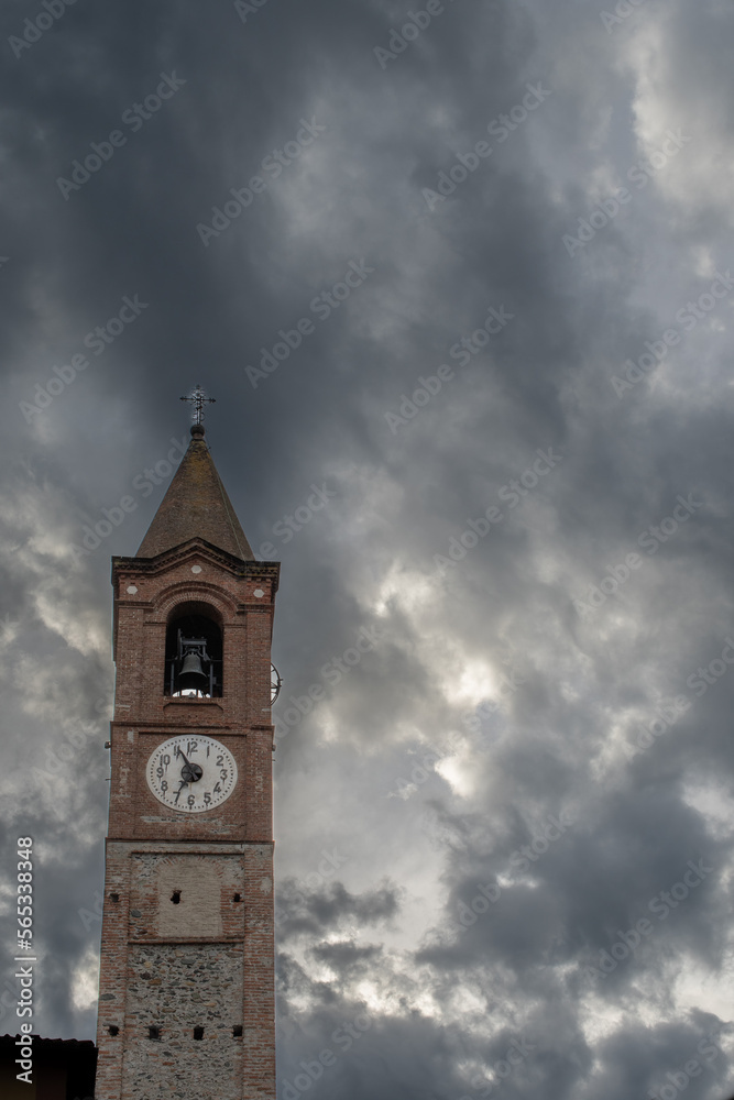 Ancient church tower in Almese, Piedmont, Italy. Bell tower with a cross and a clock.
