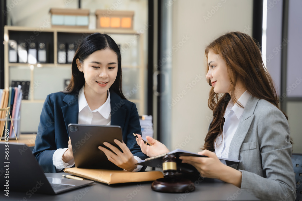 Lawyer businessman and two business partners working together in office. Business women sitting at desk and making notes. Lawyer businessman and two business partners working together in office. Business women sitting at desk and making notes.