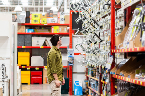 Young adult browsing tap fittings and shower heads for diy bathroom in hardware store photo