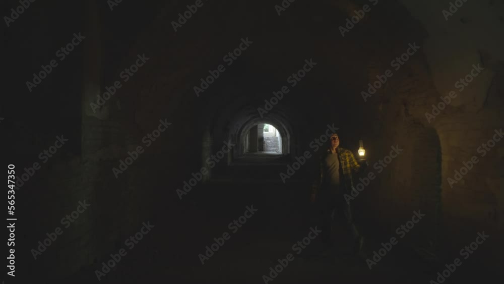 A man explores a dungeon with a kerosene lamp. Mystical atmosphere in the cave. The foundations of the castle. Old city dungeons. In the dark. High quality 4k footage