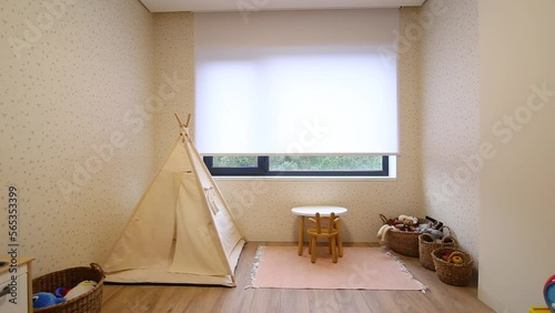 Motorized roller blinds in the children's room. Automatic roller shades on the window in the interior of child's room. Trees outside. Electric sunscreen curtains for home. Playhouse and toys there. photo