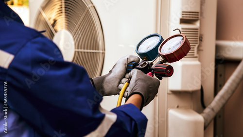 Heat and Air Conditioning, HVAC system service technician using measuring manifold gauge checking refrigerant and filling industrial air conditioner after duct cleaning maintenance outdoor compressor.