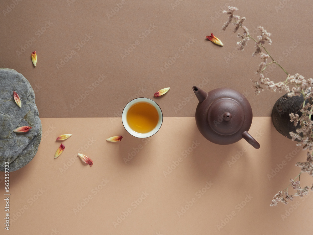 Top view of ceramic teapot and cup of hot drink placed on table near dried flowers in vase and stone with floral petals - obrazy, fototapety, plakaty 