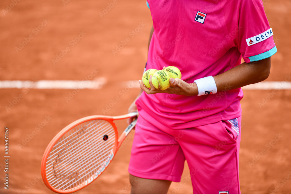 The body of a player about to serve with his racket and Wilson balls in his hands during the