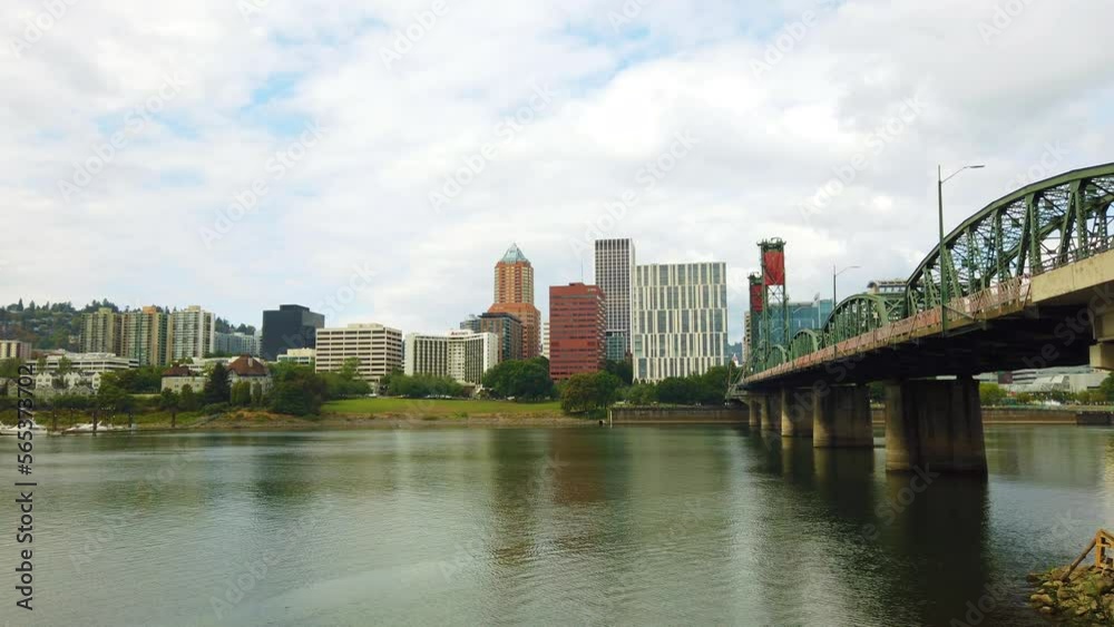 4K Boom up reveal from behind a bush to Hawthorne Bridge crossing Willamette River toward downtown Portland, Oregon skyline with mostly cloudy sky. 4K Boom up reveal from behind a bush to Hawthorne Bridge crossing Willamette River toward downtown Portland, Oregon skyline with mostly cloudy sky.