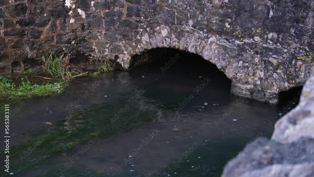 Idyllic, shallow water stream river flowing under old stone arch of bridge in rural English countryside village of Cheddar Gorge, Somerset, England Idyllic, shallow water stream river flowing under old stone arch of bridge in rural English countryside village of Cheddar Gorge, Somerset, England