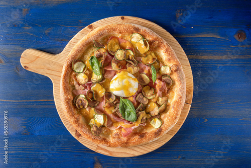 Top view of white pizza with datterino tomato cream, mozzarella, zucchini chips, Parma ham, burrata cheese, extra virgin olive oil and basil  photo