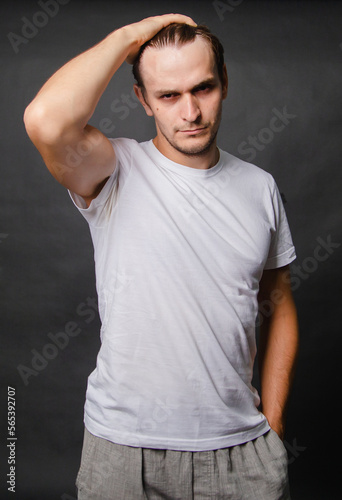 Young man in a white t-shirt on a gray background.