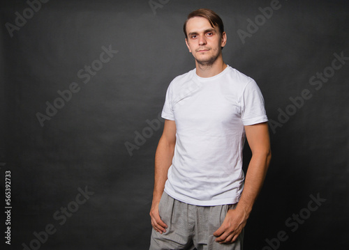 Young man in a white t-shirt on a gray background.