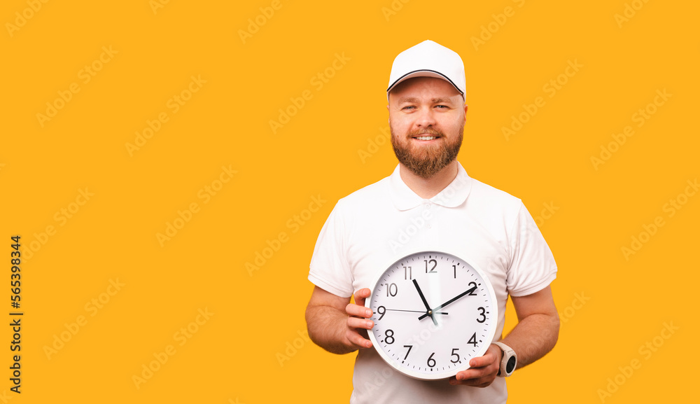 Smiling delivery man wearing white cap and t shirt is holding a round clock. Smiling delivery man wearing white cap and t shirt is holding a round clock.