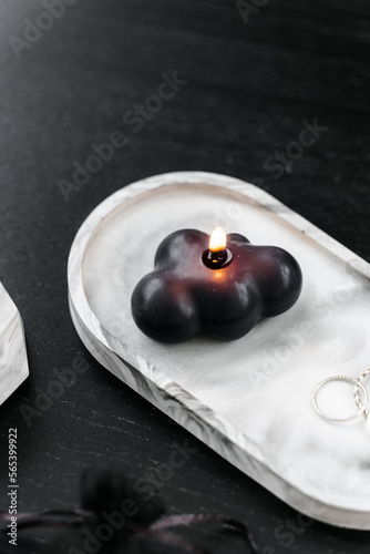 Handmade black figurative candle in a modern style, beautifully shaped. Home decor, concrete stand on black table. 
