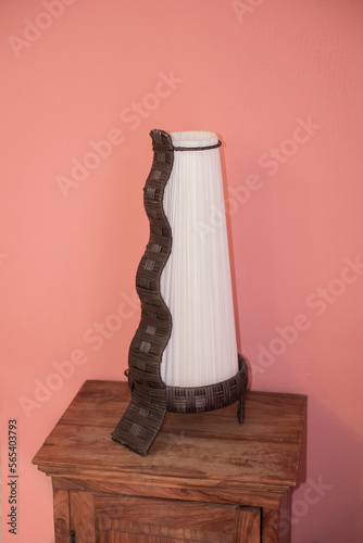 Modern lamp on a wooden table and pink wall as background