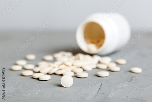 Medicine bottle and white pills spilled on a light background. Medicines and prescription pills flat lay background. White medical pills and tablets spilling out of a drug bottle