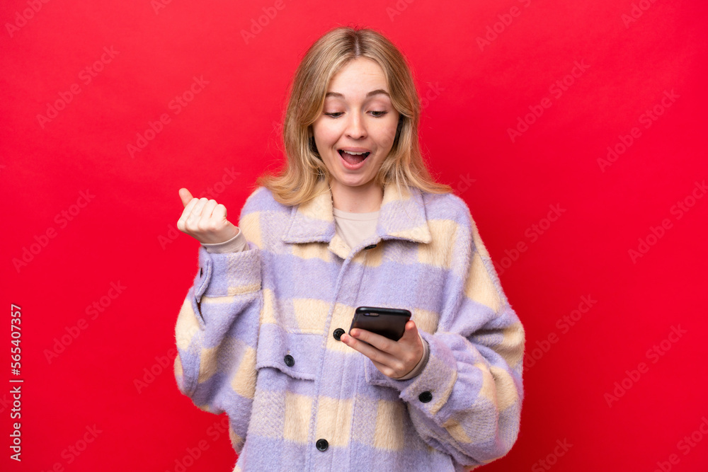 Young English woman isolated on red background surprised and sending a message Young English woman isolated on red background surprised and sending a message