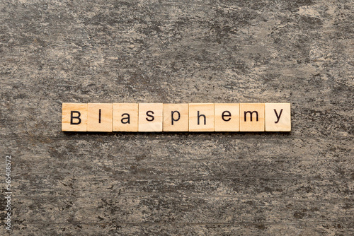 BLASPHEMY word written on wood block. BLASPHEMY text on cement table for your desing, concept photo