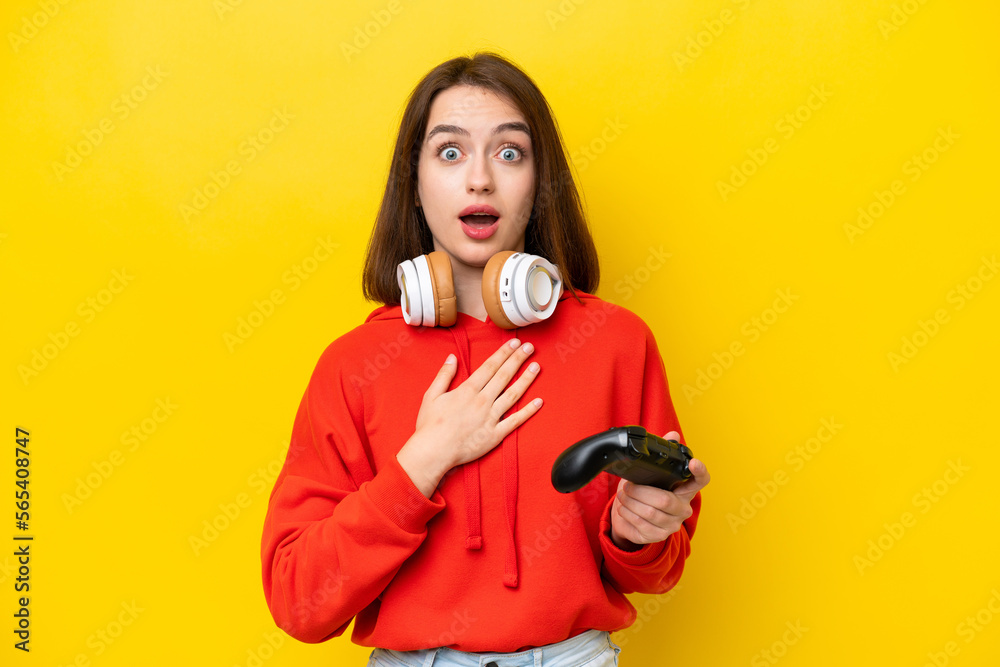 Young Ukrainian woman playing with a video game controller isolated on yellow background surprised and shocked while looking right Young Ukrainian woman playing with a video game controller isolated on yellow background surprised and shocked while looking right