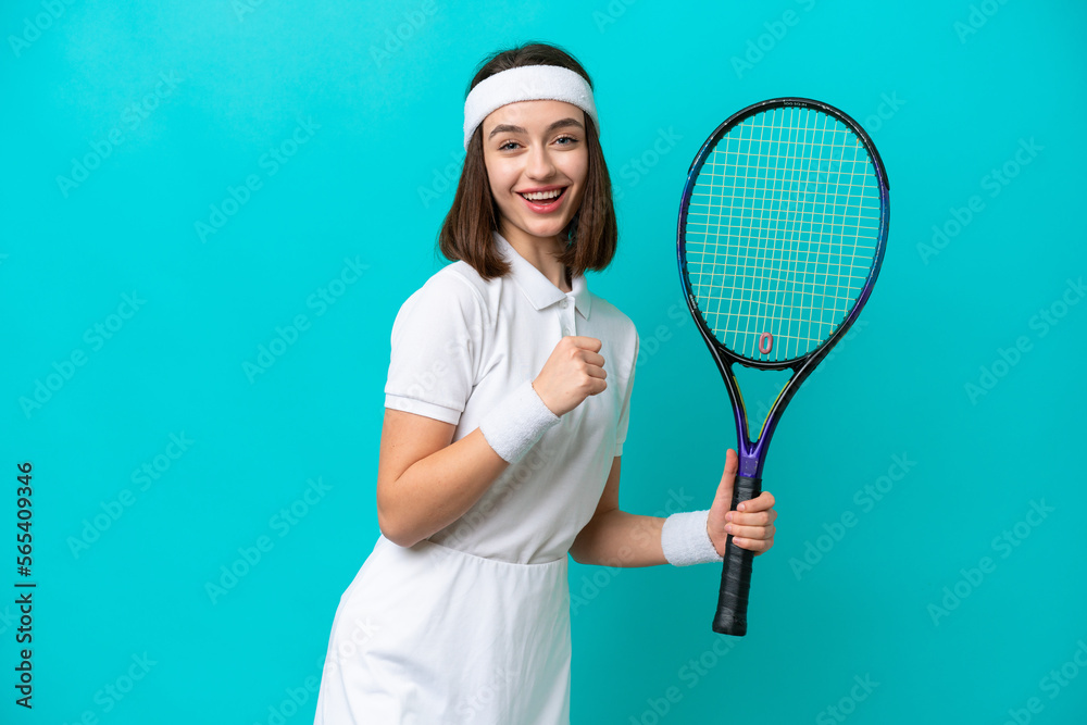 Young Ukrainian woman isolated on blue background playing tennis and celebrating a victory